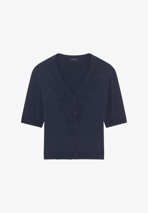 Laivastonsininen lyhythihainen neuletakki, jossa on V-pääntie, ja jonka rintakehällä on kukka-ompelu, sekä käyttäen samansävyisiä ribbireunoja ja nappia.