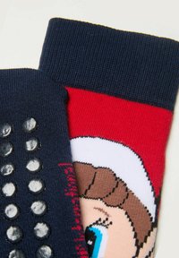 Mörkblå och röda strumpor med en texturerad marinblå rand, med ett grafiskt motiv av en vit och svart tecknad karaktär och silikongrepppunkter på ena sidan.