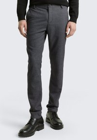 Gray textured dress pants with a slim fit, featuring a flat front and side pockets, paired with black lace-up shoes.