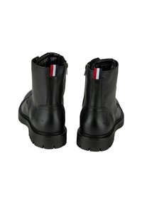 Zwarte leren enkellaarsjes met een gestructureerd oppervlak, voorzien van een achterzijde rits en een gestreepte stofaccent op de lus. Dikke rubberen zool.