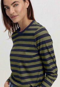 Gestreiftes Langarmshirt in Olivgrün und Marineblau. Hergestellt aus weichem Stoff, mit horizontalen Streifen und einem Rundhalsausschnitt.