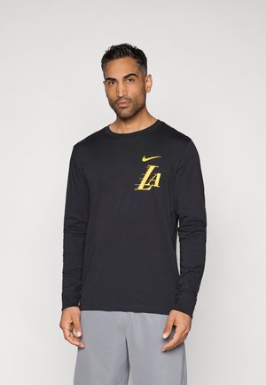 Black long-sleeve Nike T-shirt featuring a yellow LA logo on the chest. Made of soft fabric with a round neckline and fitted cuffs.