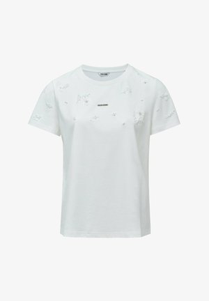 Camiseta de algodón blanca con mangas cortas, que presenta un bordado floral texturizado y una pequeña etiqueta de marca metálica en la parte delantera.