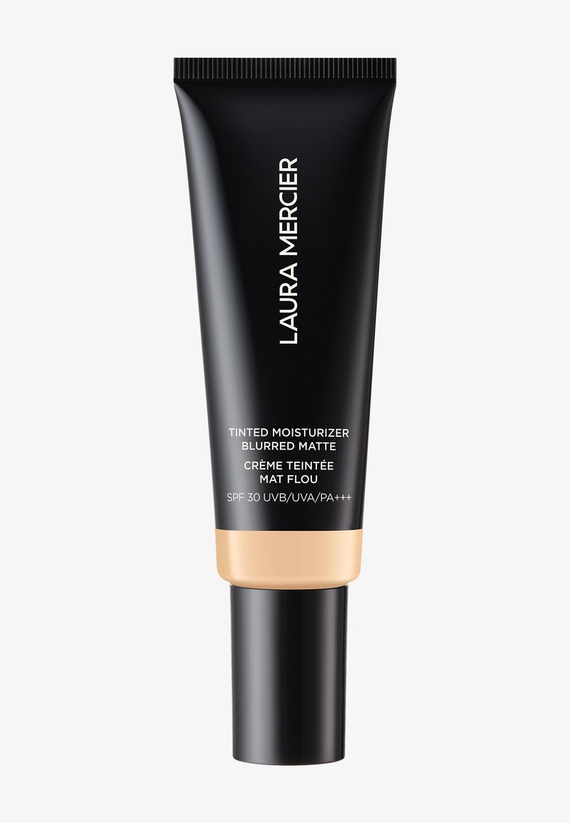 Svart tube med matt finish, gullakentering nederst, med hvit tekst. Beskriver en farget fuktighetskrem med SPF 30.