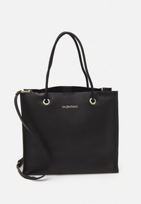 Bolsa tote de cuero negro con dos asas superiores y una correa de hombro ajustable. Presenta herrajes en tono dorado y un logotipo en la parte frontal.