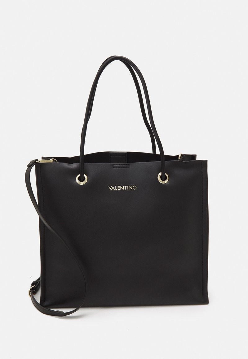 Bolsa tote de cuero negro con dos asas superiores y una correa de hombro ajustable. Presenta herrajes en tono dorado y un logotipo en la parte frontal.