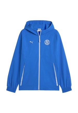 Blauwe jas met capuchon en volledige ritssluiting, elastische manchetten, twee ritssluitzakken aan de voorkant, wit Puma-logo op de rechterborst en witte ronde embleem op de linkerborst.