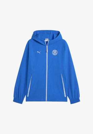Blauwe jas met capuchon en volledige ritssluiting, elastische manchetten, twee ritssluitzakken aan de voorkant, wit Puma-logo op de rechterborst en witte ronde embleem op de linkerborst.