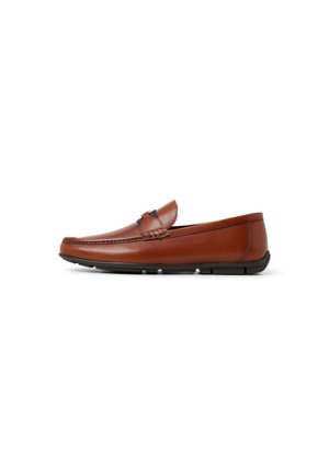 Mocasín de piel marrón con puntera redondeada, costuras decorativas y suela flexible de goma negra. Diseño de corte bajo con un ligero tacón.