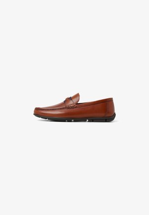 Mocasín de piel marrón con puntera redondeada, costuras decorativas y suela flexible de goma negra. Diseño de corte bajo con un ligero tacón.