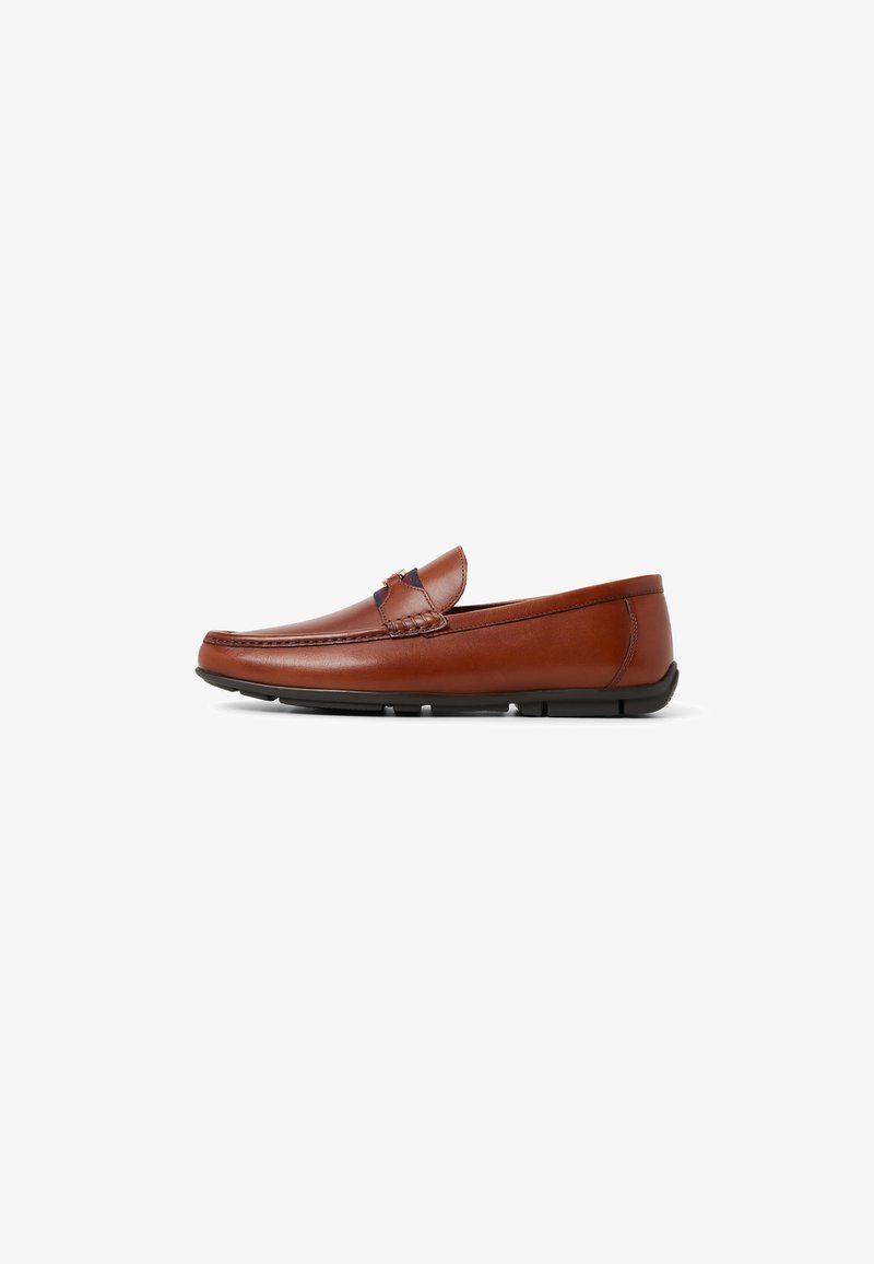 Brune læder slip-on med rund tå, dekorativ syning og en fleksibel sort gummisål. Lavskåret design med en let hæl.
