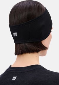 Zwarte atletische hoofdband van gestructureerde stof, voorzien van een logopatch. Draagt achter een kort kapsel en toont een eenvoudig ontwerp.
