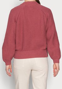 Sweter z dzianiny o fakturze, w stonowanym odcieniu różu, z prążkowanym dołem i mankietami, o luźnym kroju i z raglanowymi rękawami.