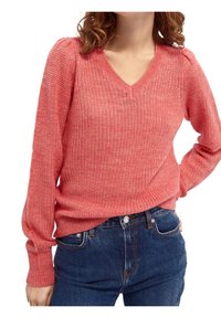 Suéter de punto de coral con escote en V, puños acanalados y tejido texturizado. Combinado con jeans de mezclilla azules. Ajuste casual y textura suave.