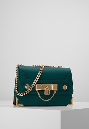 Turquoise leren handtas met schouderriem van goudkleurige ketting, rechthoekig slot en hoekaccenten, tentoongesteld op een wit platform tegen een grijze achtergrond.