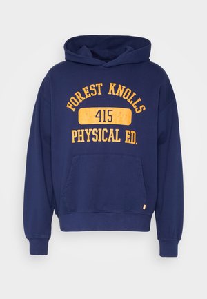 Tumši zila kapuci krekls, izgatavots no kokvilnas, ar lielu dzeltenu drukājumu uz priekšpuses, kas saka "FOREST KNOLLS PHYSICAL ED. 415".