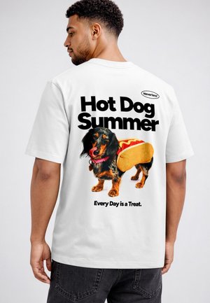Mann trägt weißes T-Shirt mit Aufdruck eines Dackels, der als Hotdog verkleidet ist, und dem Text Hot Dog Summer, Every Day is a Treat.