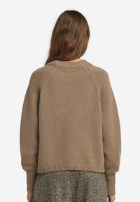 Khakifarbener Pullover mit lockerer Passform, gerippten Bündchen und weitem Ausschnitt. Verfügt über ein strukturiertes Strickdesign und einen asymmetrischen Saum.
