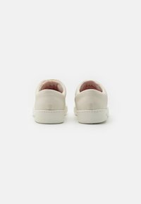 Sneaker bianchi in pelle con tallone arrotondato, interno imbottito rosa e leggero dettaglio di cucitura lungo la suola. Design semplice e minimalista.