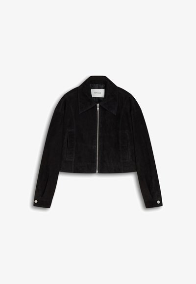 Melnā īsā jaka, izgatavota no zamšādas, ar rāvējslēdzēju priekšpusē, lielu apkakli, akcentējošiem šuvēm un pogu aizdares uz piedurknēm.