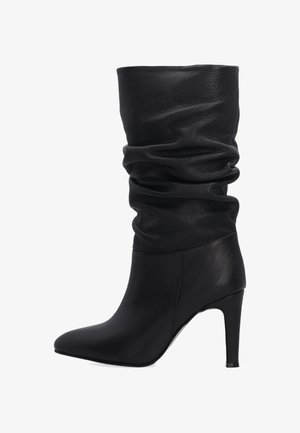 Černá kožená vysoká bota s volným designem. Obsahuje špičatou špičku a vysoký jehlový podpatek. Texturovaná kůže zajišťuje hladký vzhled.