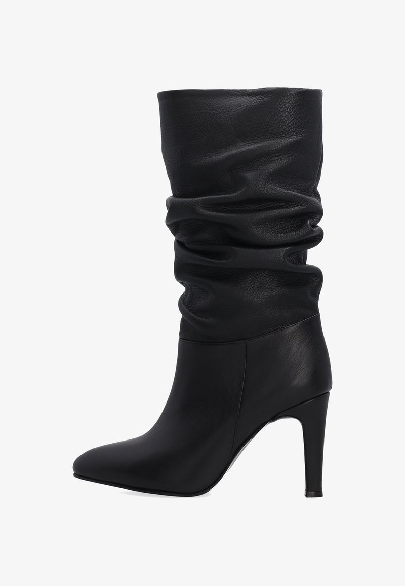 Czarne skórzane botki na obcasie z luźnym fasonem. Posiadają spiczasty czubek i wysoki obcas w kształcie szpilki. Teksturowana skóra nadaje gładki wygląd.