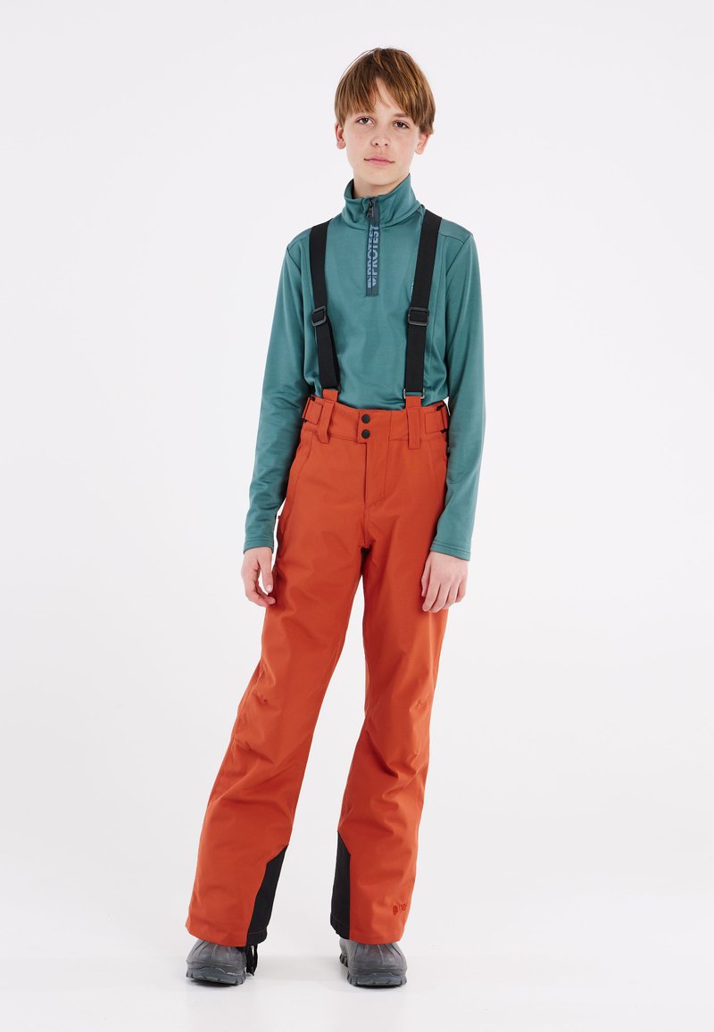 Oranje sneeuwbroeken met zwarte accenten op de onderbenen, voorzien van verstelbare banden, twee knopen en een gladde textuur, gecombineerd met een teal lange mouwen top.