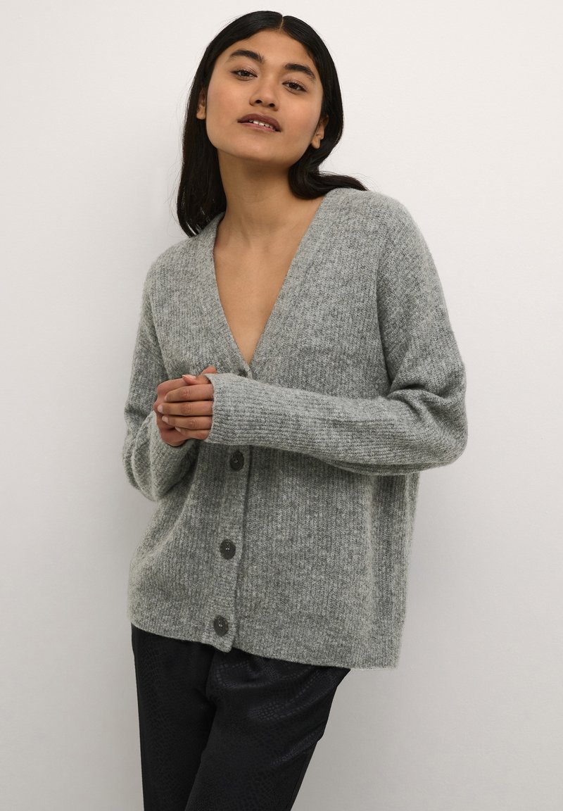 Cardigan grigio lavorato a maglia con scollo a V profondo, chiusura a bottoni e polsini a costine. Morbido al tatto e vestibilità leggermente oversized.