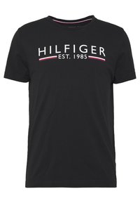 Camiseta de algodón negra con el texto blanco "HILFIGER EST. 1985" y rayas de acento rojas y azules debajo. Cuello redondo, mangas cortas.