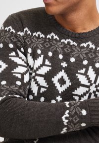 Knit sweater in dark gray with white geometric patterns, featuring a ribbed neckline and cuffs for a textured appearance.