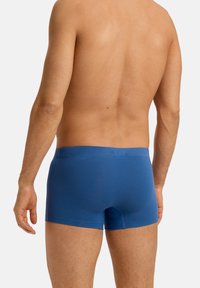 Pánské modré boxerky z bavlny s těsným střihem, elastickým pasem a hladkou texturou, s délkou ke středu stehna a bez viditelného loga.