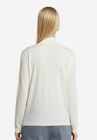 Cremefarbene Langarm-Cardigan mit weicher Textur, gerippten Bündchen und einem leicht lockeren Schnitt. Merkmale sind ein klassischer Kragen und eine Rückennahtdetails.