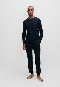 Marineblaue Langarmbluse und passende Hose, aus weichem Stoff gefertigt, mit einem Logo auf der Brust, elastischen Bündchen und einem elastischen Bund.