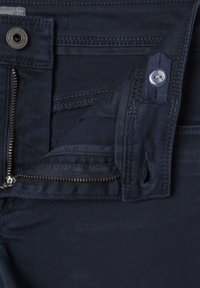 Temno modri denim kavbojki z zadrgo, gumbom za zapiranje in notranjim žepom; vsebujejo fine črte in trdno šivanje.