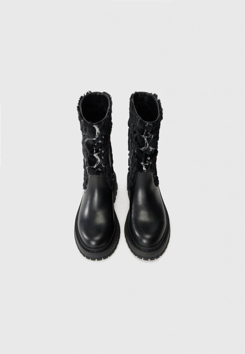 Schwarze Leder-Stiefeletten mit einem strukturierten schwarzen Fell-Obermaterial und silbernen Akzenten, ausgestattet mit einer dicken Gummisohle und einer abgerundeten Zehenpartie.