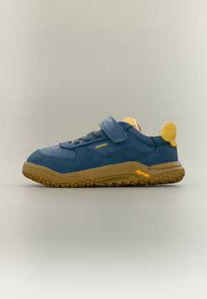 Zils un dzeltens bērnu sporta apavi ar brūnu, fakturētu zoli, Velcro siksnu un Vibram logotipu sānos, attēlots profila skatā uz neitrāla fona.