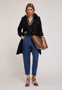 Caban negru peste un top negru cu paiete, blugi albaștri high-waisted și sandale negre cu toc. Geantă maro cu o formă structurată.