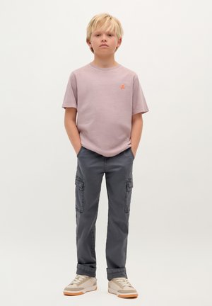 T-shirt en coton rose clair avec un logo orange, associé à un pantalon cargo gris avec poches et une coupe décontractée. Baskets beige avec un design texturé.