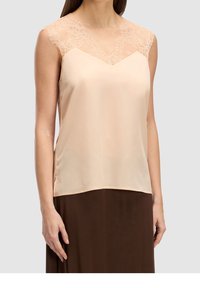 Persikka satiinihihaton paita, jossa on pitsikuvioitu yläosa ja V-mallinen kaula-aukko, ohuilla, pitsiä korostavilla olkaimilla ja suora helma.