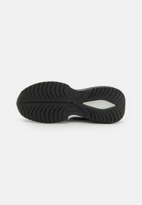 Suola di scarpa in gomma nera con motivi di battistrada testurizzati, caratterizzata da un accento bianco e una forma aerodinamica per trazione e durata.