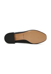 Zapato negro sin cordones con punta redondeada y tacón plano. La suela es lisa con un patrón texturizado, y cuenta con un logo estampado en la plantilla.