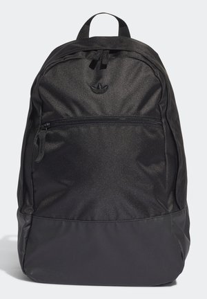 Sac à dos noir en nylon avec poche frontale zippée, poignée supérieure, et logo discret en relief sur le panneau avant supérieur.