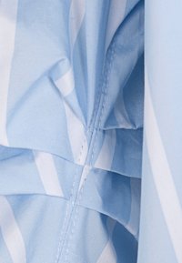 Light blue fabric with white stripes, showing a gathered seam. The material appears smooth with fine stitching details visible.