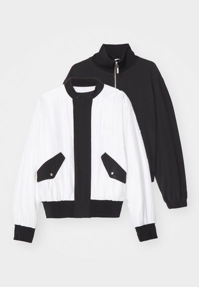 Schwarze und weiße, taillierte Jacke mit einem schwarzen Reißverschlusskragen, zwei Vordertaschen mit Druckknöpfen sowie einem gerippten Saum und Bündchen.