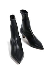 Czarne botki sięgające kostki, wykonane z gładkiej skóry, z eleganckim, spiczastym noskiem oraz zwężającą się cholewką i małym, kwadratowym obcasem. Widoczne detale szycia.