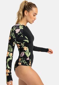 Maillot de bain à manches longues avec une base noire ornée de motifs floraux colorés en rose, orange et vert. Fermeture zippée sur le devant, design ajusté.
