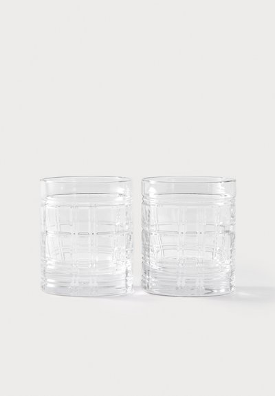 Caurspīdīgi stikla glāzes ar reljefu režģa rakstu, cilindriskas formas un gludu maliņu. Divas glāzes novietotas blakus.