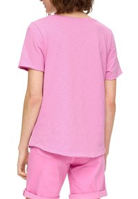 T-shirt z krótkim rękawem w jasnoróżowym kolorze, wykonany z miękkiej, strukturalnej tkaniny. Posiada okrągły dekolt oraz nieco dłuższy tylny brzeg.