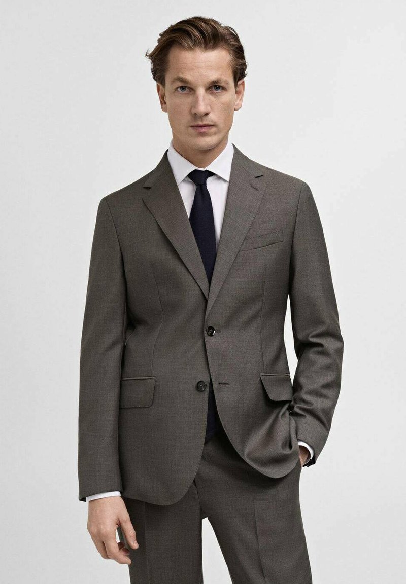 Gray tailored suit with a two-button closure, notch lapels, and side pockets. Paired with a white shirt and dark tie, displaying a sleek design.