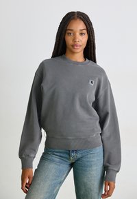 Grå fleece sweatshirt med rund hals, nedfallande axlar, ribbade ärmslut och nederkant. Har en liten logga patch på övre vänstra sidan. Avslappnad passform.